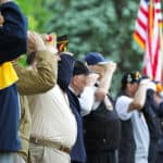Veterans saluting with American flag in the background