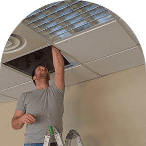 man standing on a ladder while repairing ceiling