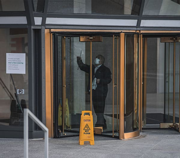 man cleaning windows of a revolving door