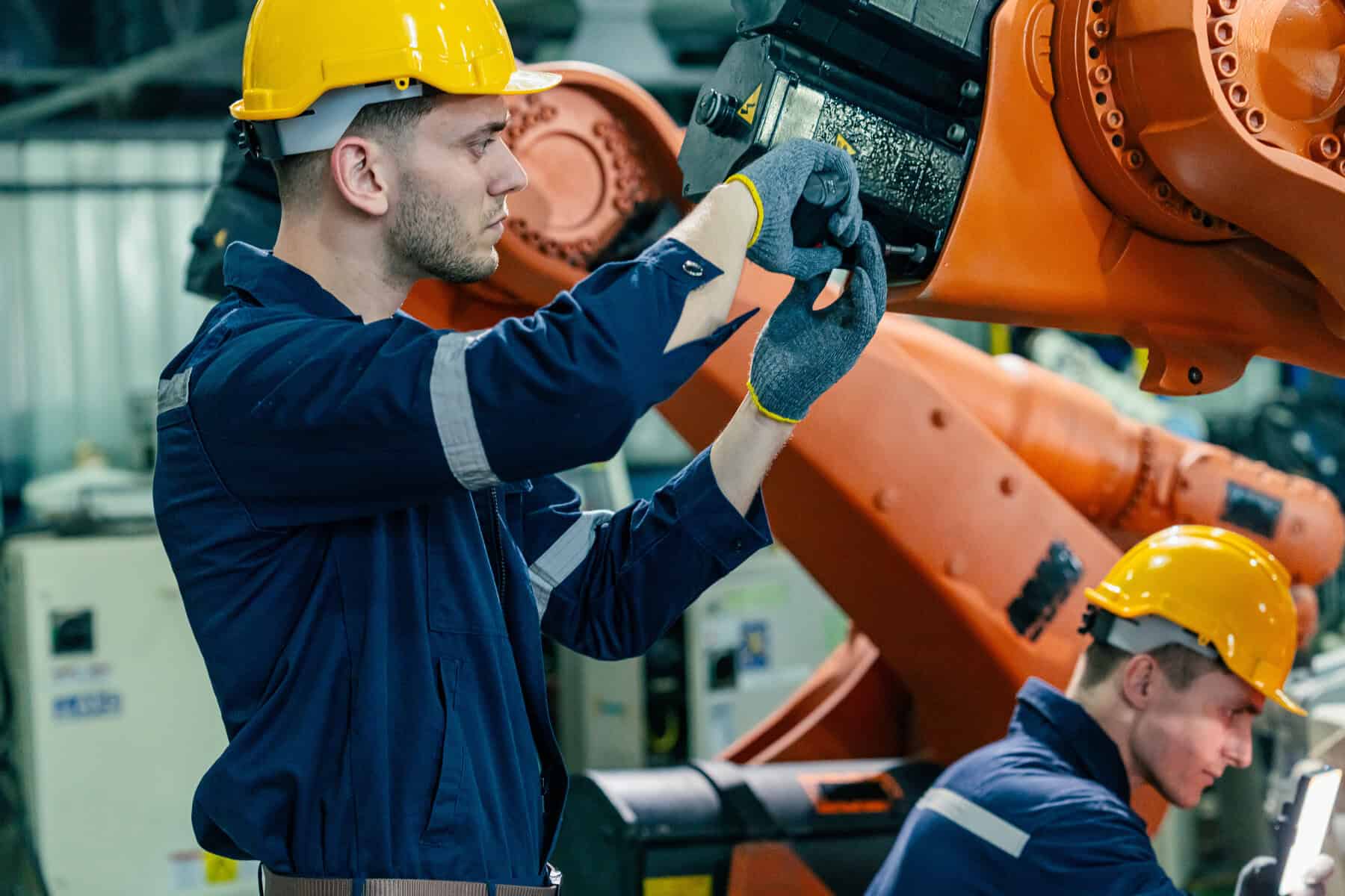 Skilled workers maintain robotic equipment in a manufacturing facility